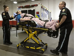 Paramedics Monica Houlihan, left, and Richard McLaughlin demonstrate the use of a hydraulic stretcher that are in use in some ambulances in Edmonton. The entire ambulance fleet is expected to be outfitted with the new equipment by March.