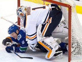 Vancouver Canucks' Derek Dorsett, left, crashes into goalie Laurent Brossoit after being tripped by Oscar Klefbom, back, of Sweden, during the second period of an NHL hockey game in Vancouver, B.C., on Saturday, October 7, 2017.