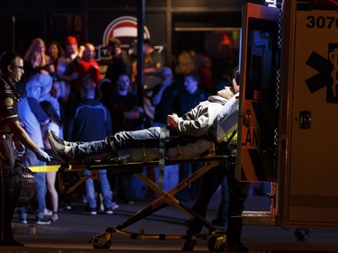 An injured person is loaded on to an ambulance outside the The Pint bar on 109 Street near Jasper Avenue after police arrested a suspect following a high-speed chase where several pedestrians were struck.