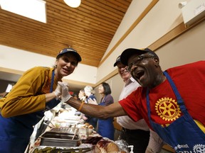 Volunteers (left to right) Nirmala Nijjar, Bruce Bradley and Okelu Chinwe celebrate during the Annual Community Thanksgiving Luncheon organized by the Millbourne Laundromat and the Rotary Club of Edmonton Southeast at Leefield Community League hall in Edmonton, Alberta on Monday, October 9, 2017.
