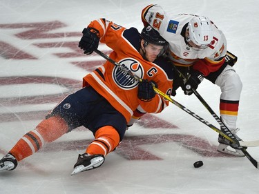 Edmonton Oilers Connor McDavid (97) gets taken down by Calgary Flames Johnny Gaudreau during the season opener of NHL action at Rogers Place in Edmonton, October 4, 2017.