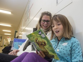 Coronation School principal Letitia Carter reads in the hallway with Grade 3 student  Brynn Van Meter. Coronation School is one of 11 public schools that participated in a U of A study on improving help for struggling young readers.