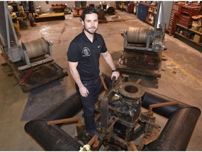 Caleb Dyck, research lead, standing on the pump and cutter dredge head, with two positioning winches in back, called the Mighty Dredge, billed as the first automated unmanned dredge in the world at Canada Pump and Power company facility east of Ardrossan, Oct. 30, 2017.