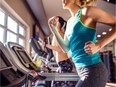 Two women runn on treadmills in a gym.