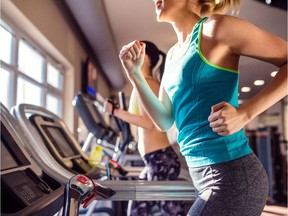 Two women runn on treadmills in a gym.