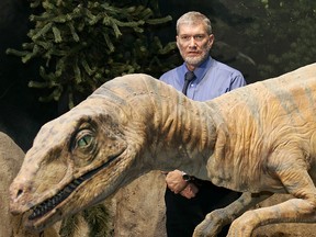 Ken Ham, president and CEO of Answer in Genesis, stands with a mechanical Utahraptor at The Creation Museum in Petersburg, Ky.