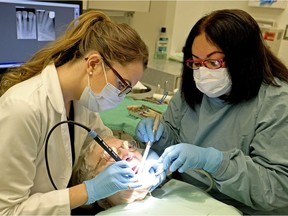 Dental patient Wilma Amirault receives treatment from Dr. Fern Leavens (left) and dental assistant Lalaine Jovellanos (right) at the Glenrose Rehabilitation Hospital in Edmonton on Nov. 22, 2017, where Alberta Health Minister Sarah Hoffman announced a new dental fee guide for Alberta that suggests a drop of 8.5 percent for sixty common dental procedures.