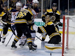 Boston Bruins goalie Tuukka Rask (40) keeps an eye on the puck as defenseman Kevan Miller (86) holds off Edmonton Oilers left wing Patrick Maroon (19) during the first period of an NHL hockey game in Boston, Sunday, Nov. 26, 2017.