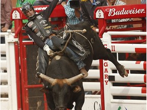 Aaron Roy of Yellow Grass, ,Sask., hangs on tight to a Bull named Nearly Departed during Day 4 at the Calgary Stampede rodeo in Calgary, Alta. on Monday July 6, 2015.