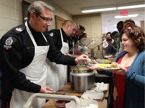 Members of the Edmonton Police Service's School Resource Officer Unit helped serve a Christmas meal at LY Cairns School on Thursday Dec. 19, 2013. School officials in Edmonton say they continue to support SROs after a decision by Toronto's school board to end its program.