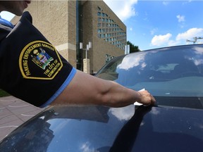 A parking enforcement officer places a ticket on a vehicle near city hall. File photo.