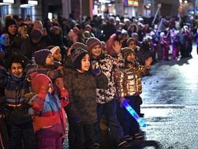 Children wave to Santa as people lined up along the street for a festive celebration of Christmas by watching Santa's Parade of Lights along Jasper Avenue in Edmonton on Nov. 18, 2017.