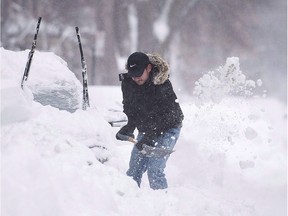 A man shovels snow from around his car following a winter storm in Montreal, Wednesday, March 15, 2017.