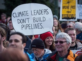A woman holds a sign during a protest and march against the Kinder Morgan Trans Mountain Pipeline expansion, in Vancouver, B.C., on Saturday, Nov.19, 2016. File photo.