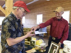 Beekeeper Jean Coppens d'Eeckenbrugge gives a sample of his Peace Gourmet Honey sweet clover honey to Andy Lozeron on Saturday August 19, 2017 during Alberta Open Farm Day at Country Roads RV Park in the County of Grande Prairie, Alta.