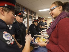 Edmonton Police Service members serve a holiday meal to Hannah Pacholok, 17, and the 450 L.Y. Cairns School students in Edmonton Thursday Dec. 21, 2017. This was the school's 38th annual holiday meal.
