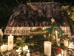 A Chapecoense soccer team poster stands behind flowers and candles left by soccer fans in Bogota, Colombia, Tuesday, Nov. 29, 2016, after many of the players died in a plane crash on Monday night. Authorities were working to finish identifying the bodies of a plane crash in Colombia before repatriating them to Brazil.