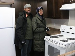 Husband and wife, Abdulahi Wozir, left, and Mebat Mohemad receive the keys for their first home at the Carter Place development site, 2216 24 St. in Edmonton, Alta., on Thursday, Dec. 21, 2017.