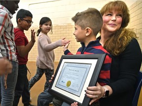 Ronan Male, 6, receives high fives after being recognized at St. Angela Catholic School on Dec. 11, 2017, by students, staff and Alberta Health Services' Emergency Medical Services who gave him a citizen lifesaving award for his quick thinking and actions that may have saved the life of his mother during a diabetic episode earlier this year.