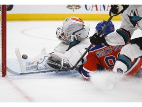 San Jose Sharks goalie Martin Jones, left, dives for the puck as Edmonton Oilers' Ryan Nugent-Hopkins crashes into him during overtime NHL hockey round one playoff action in Edmonton, Thursday, April 20, 2017.