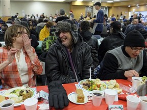 Kenney Poirier, middle, enjoys dinner with his friends at the Hope Mission in Edmonton on Monday, Dec. 4, 2017 where the first of four annual Christmas banquet dinners was held.