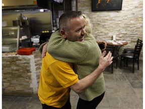 Riza Kasikcioglu, left, owner of Maximo's Pizza and Donair, gets a hug from Grace Williams, a fourth-floor resident, after he ran to save people as a fire struck the Oliver Place apartment complex at 117 Street and Jasper Avenue in Edmonton, Alberta on Thursday, Jan. 19, 2017. Five hundred people were evacuated in the two-alarm fire.