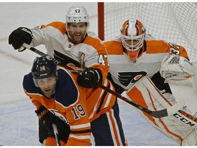 Edmonton Oilers forward Patrick Maroon is checked by Philadelphia Flyers' Andrew MacDonald in front of goalie Brian Elliott in Edmonton on Wednesday, Dec. 6, 2017.