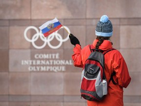 A woman waves a Russian flag in front of International Olympic Committee headquarters in Lausanne, Switzerland, on Dec. 5.