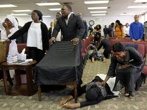 Congregation members collapse as they are overcome with grief and anguish during a church service at Solid Rock Church International in Edmonton on Sunday September 24, 2017. Three women from the church congregation died and a fourth was transported to hospital in Edmonton after a stolen heavy-duty, flat-deck truck collided with a minivan on Highway 16 east of Edmonton. The wife of the church pastor was one of the victims killed in the crash. The chair draped in a black cloth is the seat that the pastor's wife used to sit in during church services. An ambulance was called to the church to treat the members who collapsed in grief.