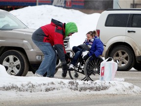 A Good Samaritan helps a woman in a wheelchair who became stuck in the ice and snow while crossing 116 Street at 104 Avenue, in Edmonton. File photo.
