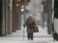 A pedestrian makes her way through the blowing snow along Jasper Avenue near 102 Street, in Edmonton Alta. File photo.