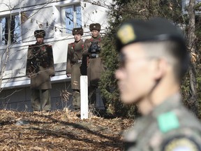 In this Nov. 27, 2017, file photo, North Korean soldiers look at the South side as a South Korean stands guard.