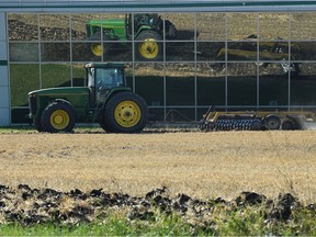 A tractor is reflected in the Agri-Food Discovery Place building windows while tilling a field at University of Alberta farm in Edmonton, Sept. 7, 2017.