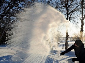 Adele Edwards demonstrates how, when it's very cold out, boiling water will vaporize instantly if thrown in the air in Edmonton on  Dec. 4, 2013.