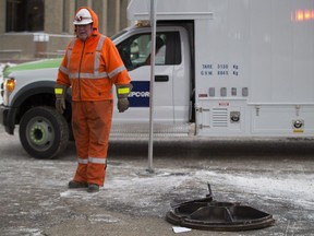 A worker stands near the area where an underground explosion occurred blowing a manhole cover off on Wednesday, Jan. 10, 2018 in Edmonton. A woman fell into the hole and was subsequently rescued after suffering minor injuries.
