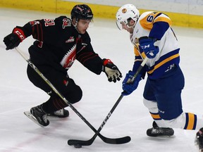 Saskatoon Blades' Josh Paterson moves the puck past Moose Jaw Warriors' Kale Clague during first period action at SaskTel Centre in Saskatoon, SK on January 21, 2018.