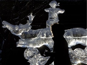 A woman walks past an ice sculpture during the Ice on Whyte festival in Edmonton.