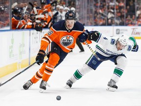 EDMONTON, AB - JANUARY 20: Jesse Puljujarvi #98 of the Edmonton Oilers battles against Michael Del Zotto #4 of the Vancouver Canucks at Rogers Place on January 20, 2018 in Edmonton, Canada.