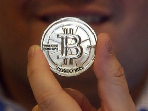 A man holds a 25 Bitcoin token in Sandy, Utah in an April 3, 2013 file photo. When most Canadians think of Drumheller, they conjure up images of dinosaur bones and ancient fossils. But entrepreneur Sean Clark's expedition in the northern Alberta town is focused on a very current obsession: Bitcoin.