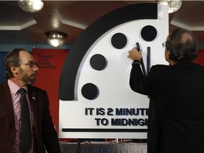 Robert Rosner, chairman of the Bulletin of the Atomic Scientists, right, joined by Bulletin of the Atomic Scientists member Lawrence Krauss, left, moves the minute hand of the Doomsday Clock to two minutes to midnight during a news conference at the National Press Club in Washington, Thursday, Jan. 25, 2018.