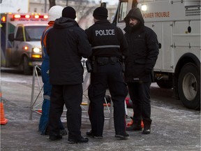 Police and emergency responders stand around the area where an underground explosion occurred blowing a manhole cover off on Wednesday, Jan. 10, 2018 in Edmonton.