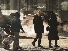 People cross the street at Jasper Avenue and 109 Street on a cold day in Edmonton, Alberta on Thursday, January 11, 2018.