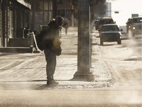 A pedestrian waits in the cold to cross the street at Jasper Avenue and 109 Street on a cold day in Edmonton, Alberta on Thursday, January 11, 2018.