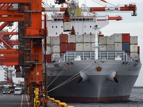 Cranes load containers onto a cargo ship at a pier in Tokyo. The 11 members of the Trans-Pacific Partnership agreed a deal Tuesday.