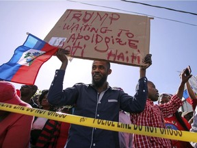 Haitian community members protest near President Donald Trump's Mar-a-Lago estate Monday, Jan. 15, 2018, in West Palm Beach, Fla. Trump is defending himself anew against accusations that he is racist, this time after recent disparaging comments about Haiti and African nations. The group said they were there to demand an apology from the Trump.