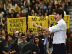 Protesters against pipelines hold up their signs while Prime Minister Justin Trudeau answers questions at a town hall meeting at MacEwan University in Edmonton, February 1, 2018.