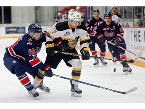 Luka Burzan, 27, of the Brandon Wheat Kings is knocked off the puck by the Regina Pats' Brady Pouteau on Tuesday in Brandon.
