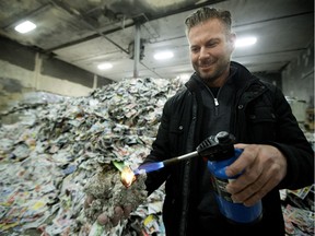 Karl Tiemstra, vice-president of operations at Can-Cell Industries, holds a propane torch to a handful of insulation as he demonstrates the nonflammable properties of the product at the company's insulation plant in Edmonton on Wednesday, Feb. 14, 2018. Can-Cell makes the insulation out of source-separated recycled newspaper.