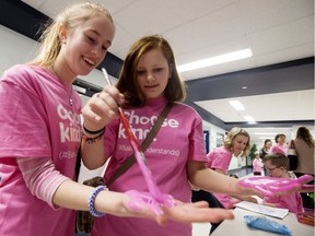 Balwin School students Carissa Jameson, 13, left, and Annie Fowler, 15, paint their hands pink as they prepare to add pink hand prints to the school's anti bullying pledge during Pink Shirt Day in Edmonton Wednesday, Feb. 28, 2018.