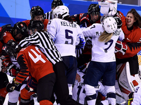 Players pile up on the Canadian goal in the women's preliminary round ice hockey match between the US and Canada.